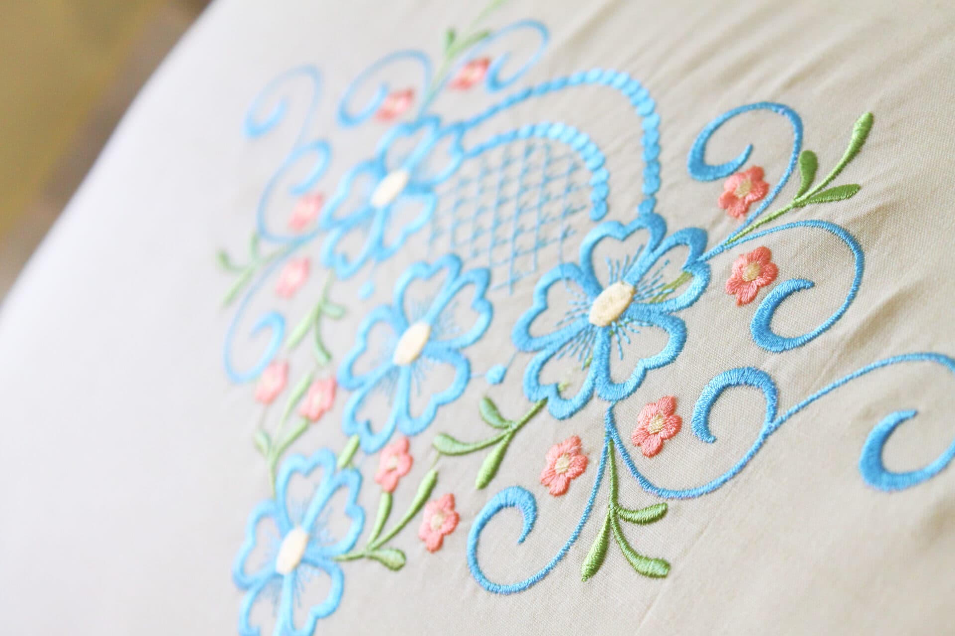 Detalle de flores bordadas en azul y rosa sobre lino